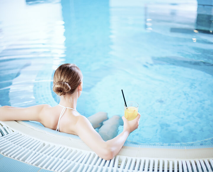 Frau im Pool mit Cocktail